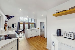A modern kitchen with a central island, a dining area with a table and chairs, and a built-in oven.