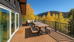 Une terrasse dotée d’une table et de bancs, offrant une vue sur un paysage montagneux aux couleurs automnales.