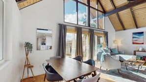 Une pièce spacieuse comprenant une table à manger, des chaises, un canapé et une grande fenêtre avec des rideaux.
