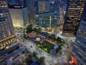 A cityscape with high-rise buildings, a central plaza with seating areas, and a bus stop. - Lux Mins to /Wayne State/ & /DMC/ Ford Field/ MGM (Detroit)