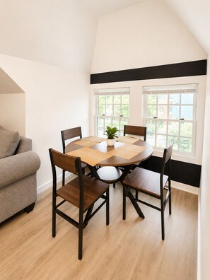 A dining area with a round table, four chairs, a potted plant, and a sofa. - Lux Mins to /Wayne State/ & /DMC/ Ford Field/ MGM (Detroit)