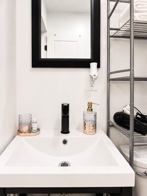 A bathroom with a white sink, a black faucet, a glass soap dispenser, and a mirror with a black frame. - Lux Mins to /Wayne State/ & /DMC/ Ford Field/ MGM (Detroit)