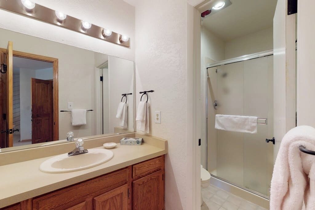 Une salle de bain avec un grand miroir, un lavabo, une douche et un porte-serviettes.