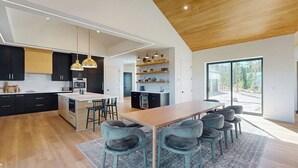 A modern kitchen with a central island, black cabinets, and pendant lighting. - Modern home with a hot tub, game room and fabulous deck space! (Tabernash)