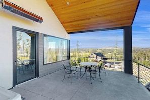 Ein moderner Balkon mit Holzboden, Glastüren und einem Tisch mit Stühlen.