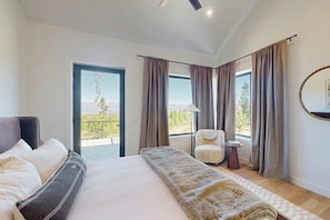 Ein Schlafzimmer mit Bett, Stuhl, Lampe und Blick ins Freie.