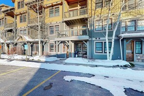 Ein mehrstöckiges Hotel mit Balkonen, einem Parkplatz und Schnee.
