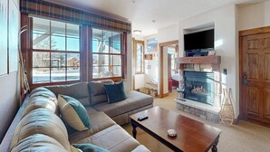 Una sala de estar con sofá, mesa de centro, chimenea y televisor.