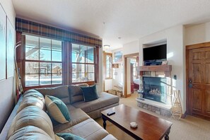 Ein Wohnzimmer mit einer Couch, einem Couchtisch, einem Kamin und einem Fernseher.