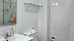 Ein Badezimmer mit Waschbecken, Spiegel, Toilette und Duschkabine aus Glas.