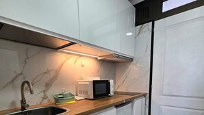 Eine moderne Küche mit weißen Schränken, einer Edelstahl-Spüle, einer Mikrowelle und einer Holz Arbeitsplatte.