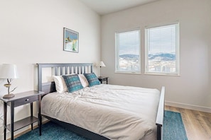 A bedroom with a bed, two bedside tables, a lamp, a framed picture, and a window with a view. - Charming townhouse with mountain views, gas fireplace, and dog friendly (Tabernash)
