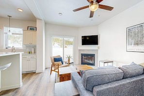 A modern living room with a sofa, a fireplace, a television, and a ceiling fan. - Charming townhouse with mountain views, gas fireplace, and dog friendly (Tabernash)