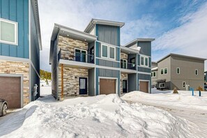 A multi-story residential building with a stone facade, balconies, and a garage. - Charming townhouse with mountain views, gas fireplace, and dog friendly (Tabernash)
