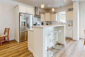 A modern kitchen with white cabinetry, stainless steel appliances, and a central island with bar stools. - Charming townhouse with mountain views, gas fireplace, and dog friendly (Tabernash)
