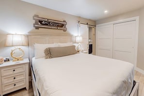 Ein Schlafzimmer mit einem Bett, Nachttischen, einem an der Wand befestigten Schild und einem Kleiderschrank.