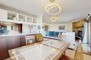 A modern kitchen with a dining area, a stone fireplace, and a view of the outdoors. - Mountain Getaway condo with wood burning fireplace close to adventure (Granby)