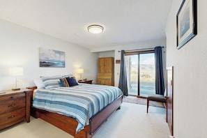 A bedroom with a bed, nightstands, a wooden cabinet, a chair, and a view of the outdoors. - Mountain Getaway condo with wood burning fireplace close to adventure (Granby)