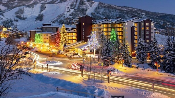 Hotel com vários andares, uma pista de esqui ao fundo e paisagem coberta de neve.