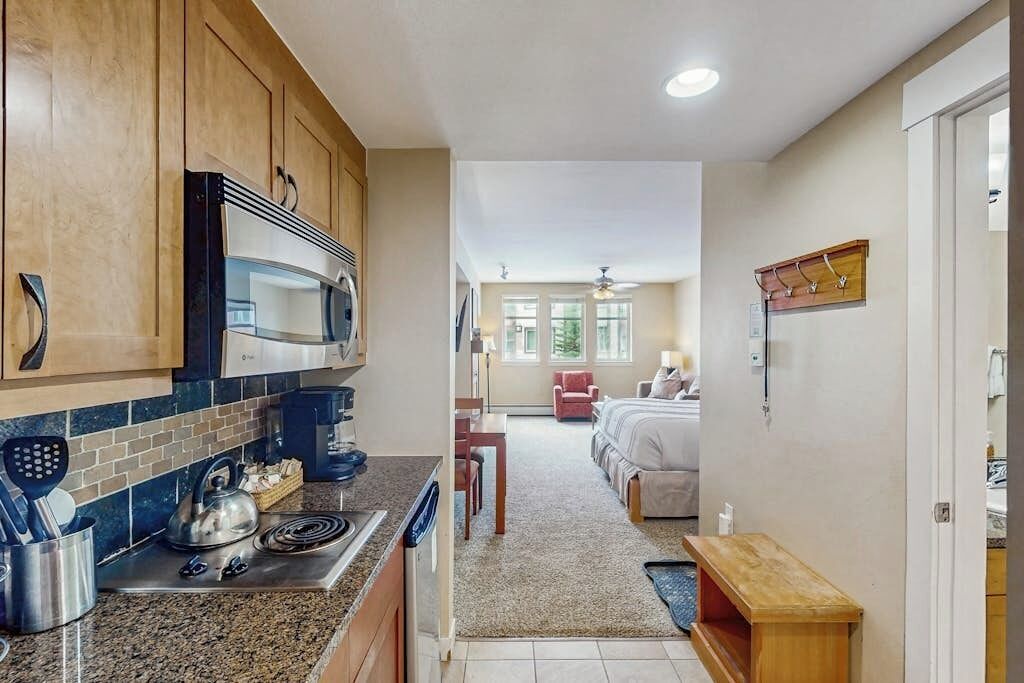 A compact kitchen with modern appliances, a dining area, and a bedroom with a view.