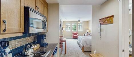 A compact kitchen with modern appliances, a dining area, and a bedroom with a view.