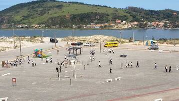 Ein Parkplatz mit Spielplatz, Bushaltestelle und Blick auf See und Hügel.