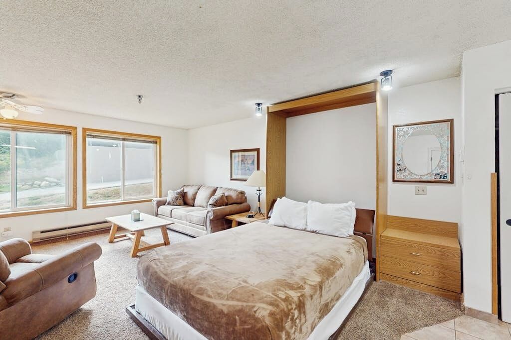 A bedroom with a large bed, a sofa, a small table, and a wooden headboard.