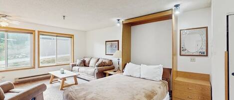 A bedroom with a large bed, a sofa, a small table, and a wooden headboard.