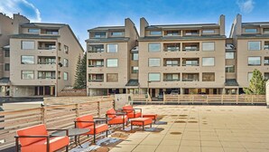 Een hotel met meerdere verdiepingen, met een terras op het dak, zitplaatsen buiten en uitzicht op de omgeving.