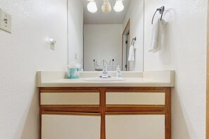 Une salle de bain avec un meuble-lavabo en bois, un miroir et un porte-serviettes.