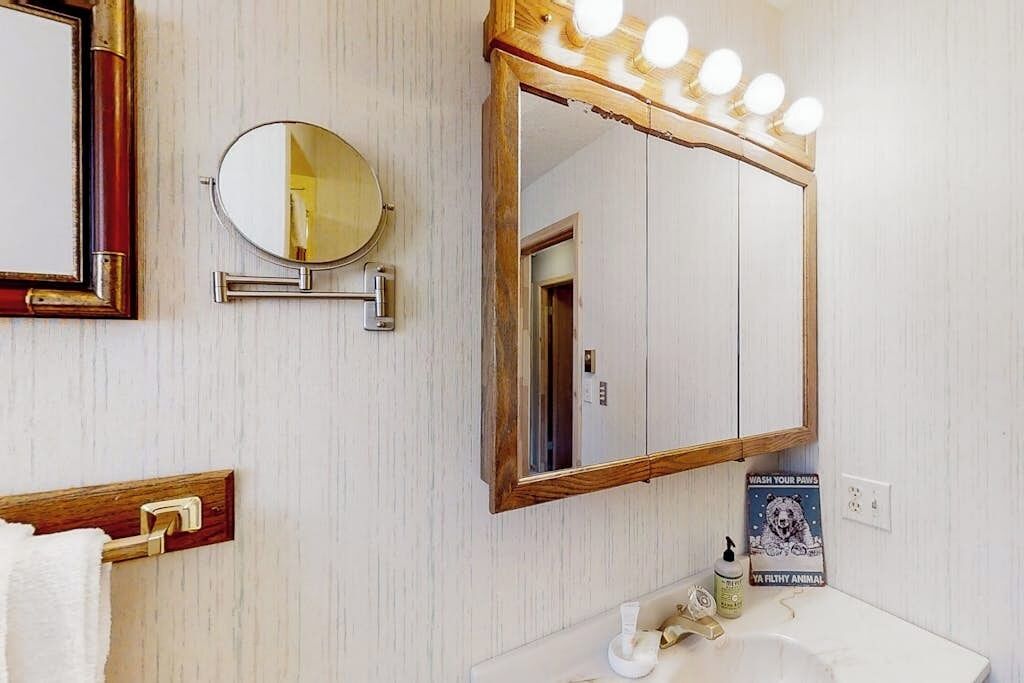 Un bagno con uno specchio grande, un mobile lavabo e un poster appeso al muro.