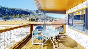 Ein Balkon mit Tisch und Stühlen, eine Steinmauer und Blick auf eine verschneite Landschaft.