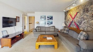 A living room with a TV, sofa, coffee table, and artwork. - Mountain & lake views from this Lake Cliffe condo - clubhouse access (Dillon)