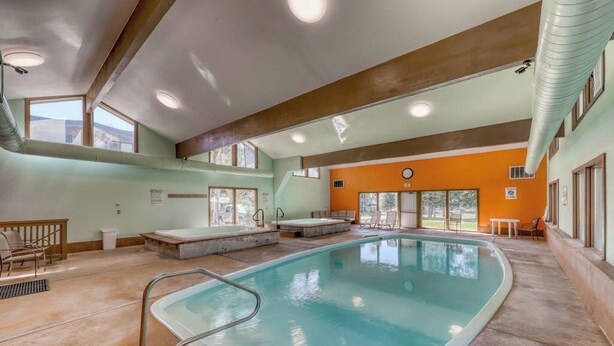 An indoor swimming pool with a diving board, a lounge area with chairs, and a view of the outdoors. - Mountain & lake views from this Lake Cliffe condo - clubhouse access (Dillon)