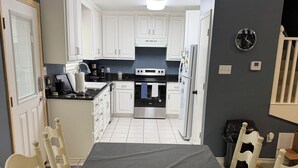 Una cocina con gabinetes blancos, una encimera negra y una mesa de comedor con sillas.