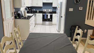Une cuisine avec des meubles blancs, un plan de travail noir et une table à manger avec des chaises.