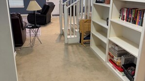 Una habitación con una estantería, una silla, una lámpara y una puerta con un letrero encima.