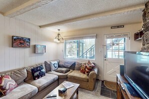 A cozy living room with a sectional sofa, a flat-screen TV, and a stone accent wall.