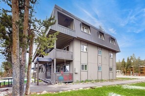 A multi-story building with a balcony, a staircase, and a flat roof.