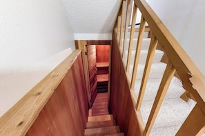 Un escalier en bois, avec un mur blanc et une rampe en bois.