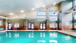 Una piscina interior con agua cristalina, un trampolín y suelo de baldosas.