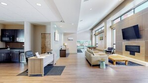 Un vestíbulo moderno con mostrador de recepción, zona de estar y mesa de billar.