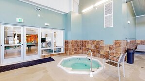 Un área de piscina con un jacuzzi, una silla y un bote de basura.