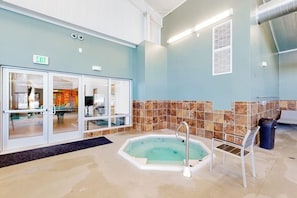 Ein Poolbereich mit Whirlpool, einem Liegestuhl und einem Mülleimer.