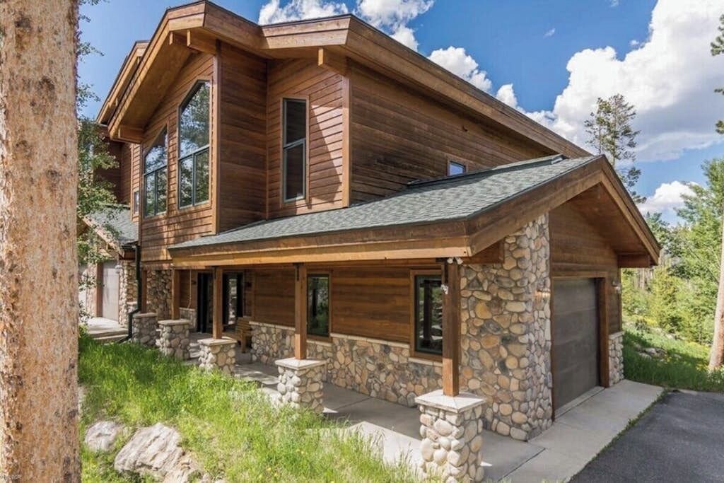 A two-story log cabin with stone foundation, large windows, and a garage.