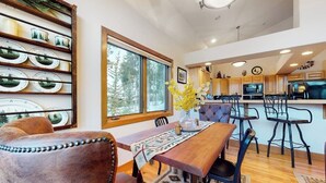 Un coin repas avec une table en bois, des chaises et une vue sur la cuisine.