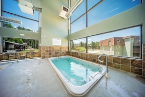 Ein Wellnessbereich mit Whirlpool, großen Fenstern und Blick auf Gebäude.