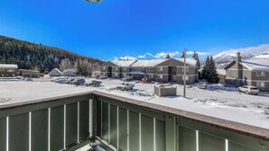 A residential area with multiple houses, a parking lot, and a snowy landscape with mountains in the background. - Mountain view condo w/ a shared pool, hot tub, Ping-Pong, & pool table (Dillon)