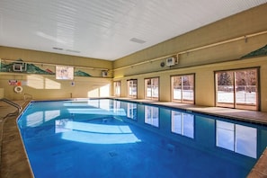 Ein großes Hallenbad mit klaren Fenstern, Fliesenboden und einer Decke mit Belüftung.