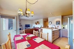 A compact living space with a dining area, kitchenette, and a TV in the background. - Wildernest Condo Close to Top Ski Resorts  + Free WiFi (Silverthorne)